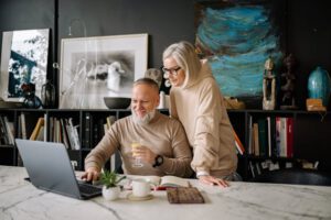 Glückliches Ehepaar sucht im Internet nach Fördermöglichkeiten für den altersgerechten Umbau