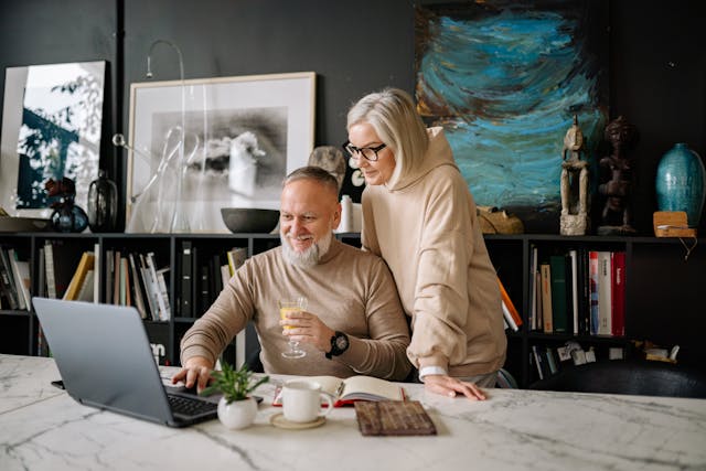 Glückliches Ehepaar sucht im Internet nach Fördermöglichkeiten für den altersgerechten Umbau