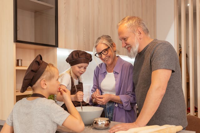 Großeltern mit ihren Enkeln in der Küche am Kochen